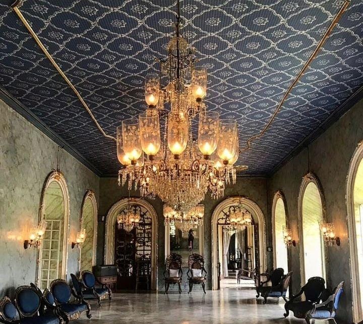 Two luxurious royal chairs from spain positioned between large ornate mirror, adding a touch of sophistication to the ballroom.