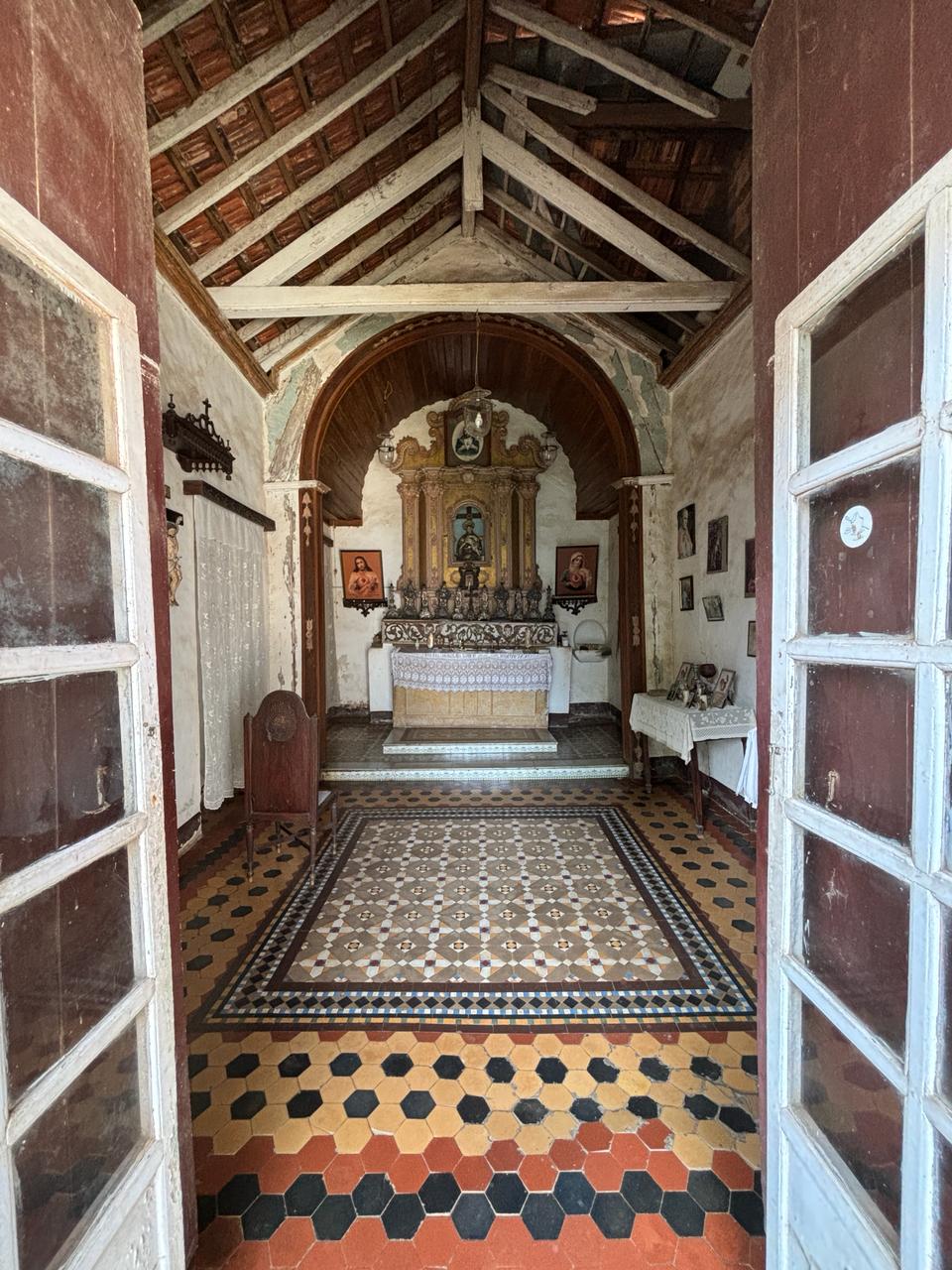 Interior view of the chapel featuring the intricately carved wooden altar and soft light filtering through stained glass door.