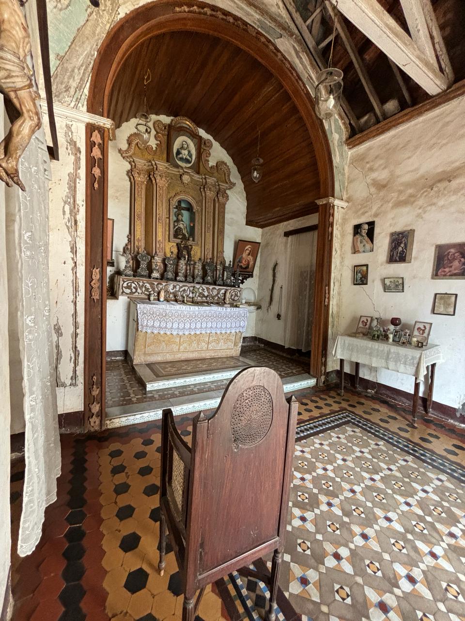 the antique confession chair in the chapel, featuring intricate carvings and a plush seat, evoking a sense of history and spiritual significance.