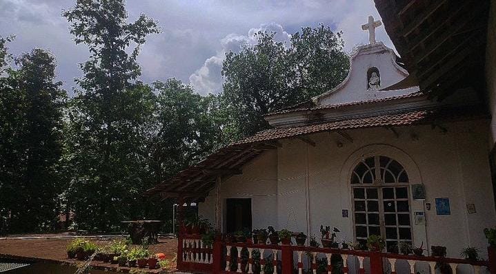 Exterior view of the chapel at Braganza House, showcasing its charming architecture framed by lush greenery and traditional Goan style.