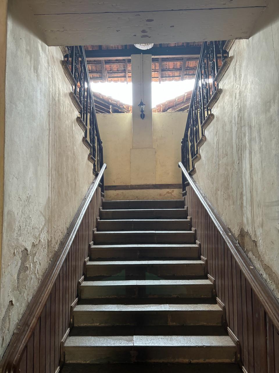 Grand entrance of Braganza House featuring a majestic staircase, leading to ornate doors and elegant decor.